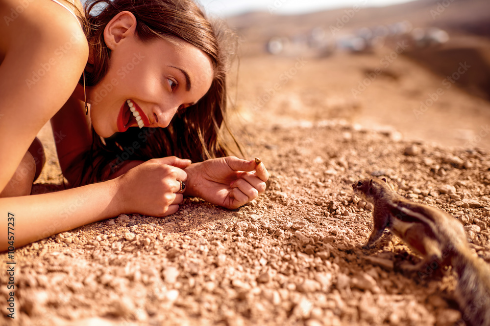 Excited woman feeding moorish squirrel on Fuerventura island in Spain