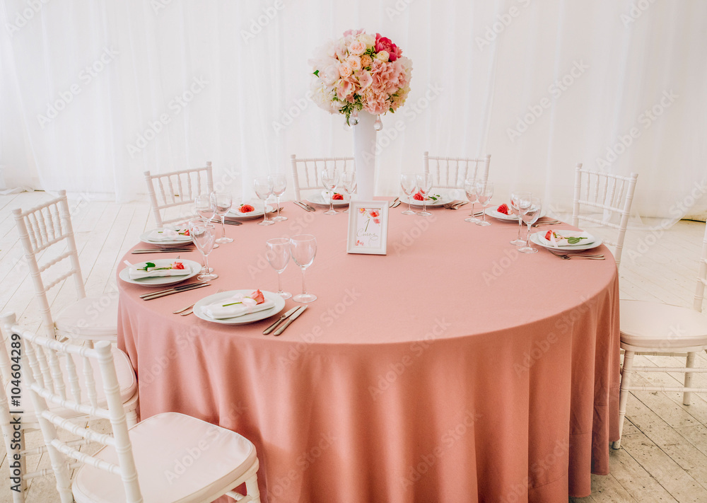 The decor table with pink tablecloth and bouguet of roses