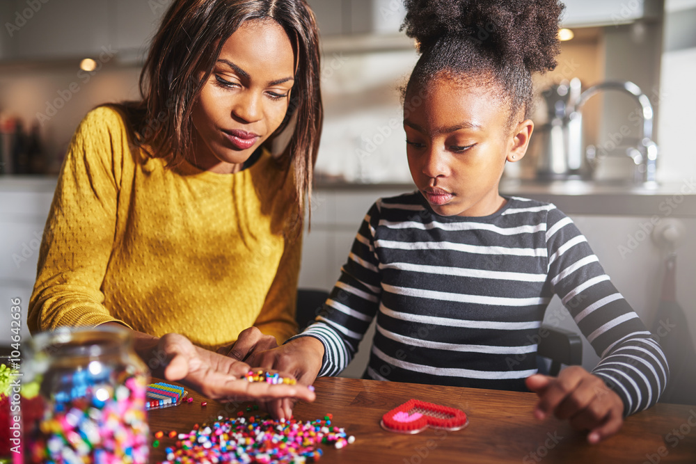 Girl choosing beads from hand of woman