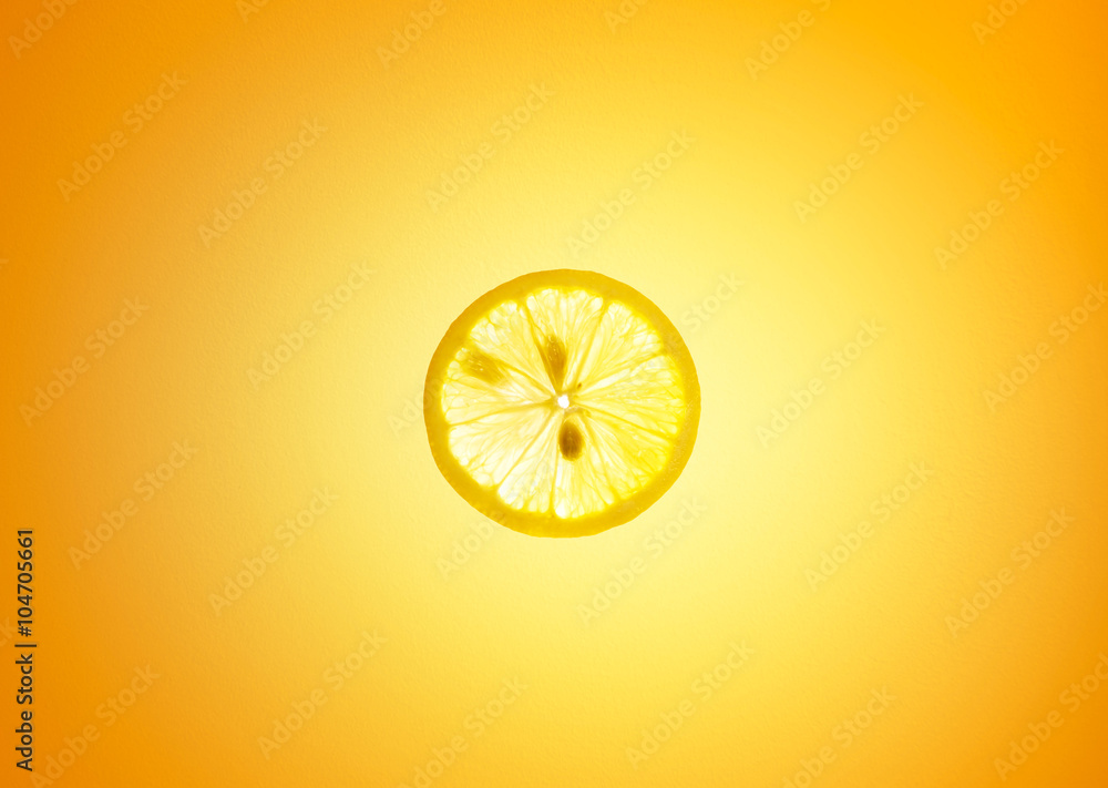 Lemon on orange background , back lit .