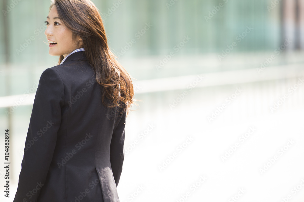 Woman wearing a business suit is turned around with a smile