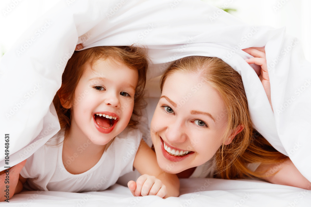 happy family mother and child playing and laughing in bed