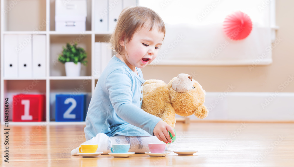 Toddler girl have tea with her teddy bear