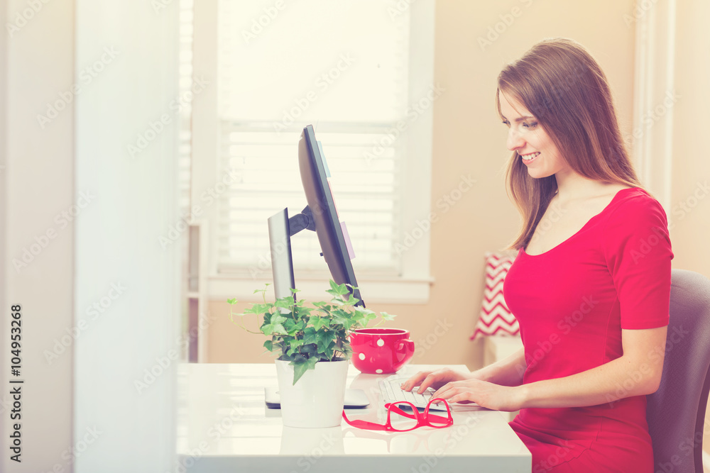 Happy young woman on her computer in her home office