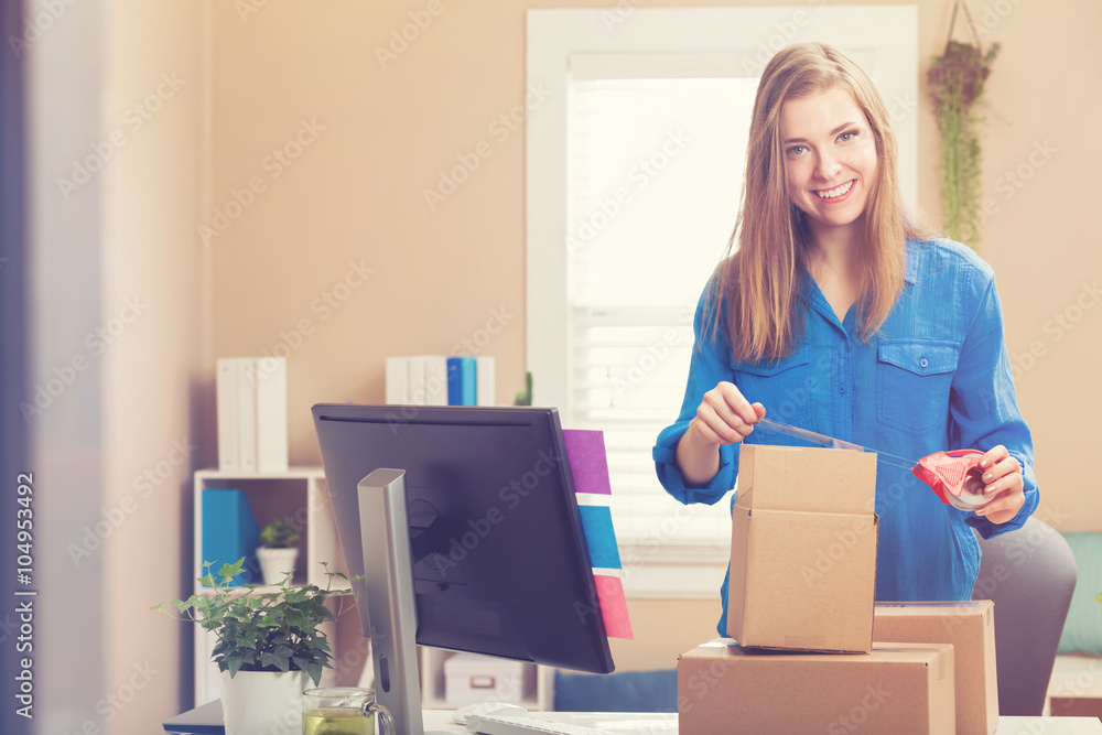 Woman taping boxes to be shipped in her home office