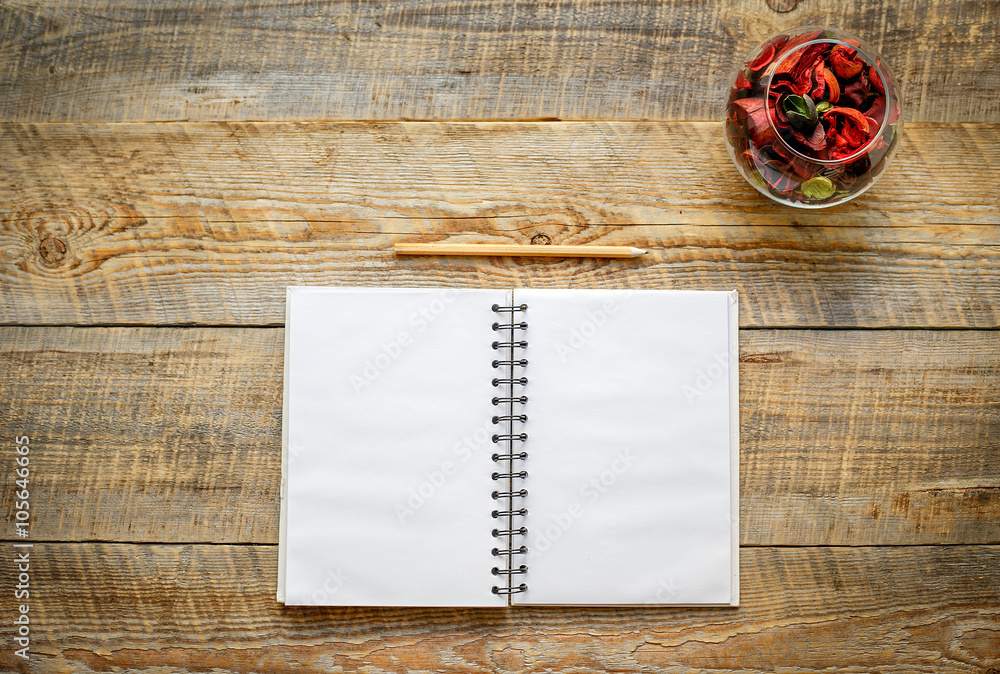 Open blank notebook next to pencils on wooden table