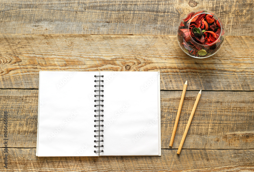 Open blank notebook next to pencils on wooden table