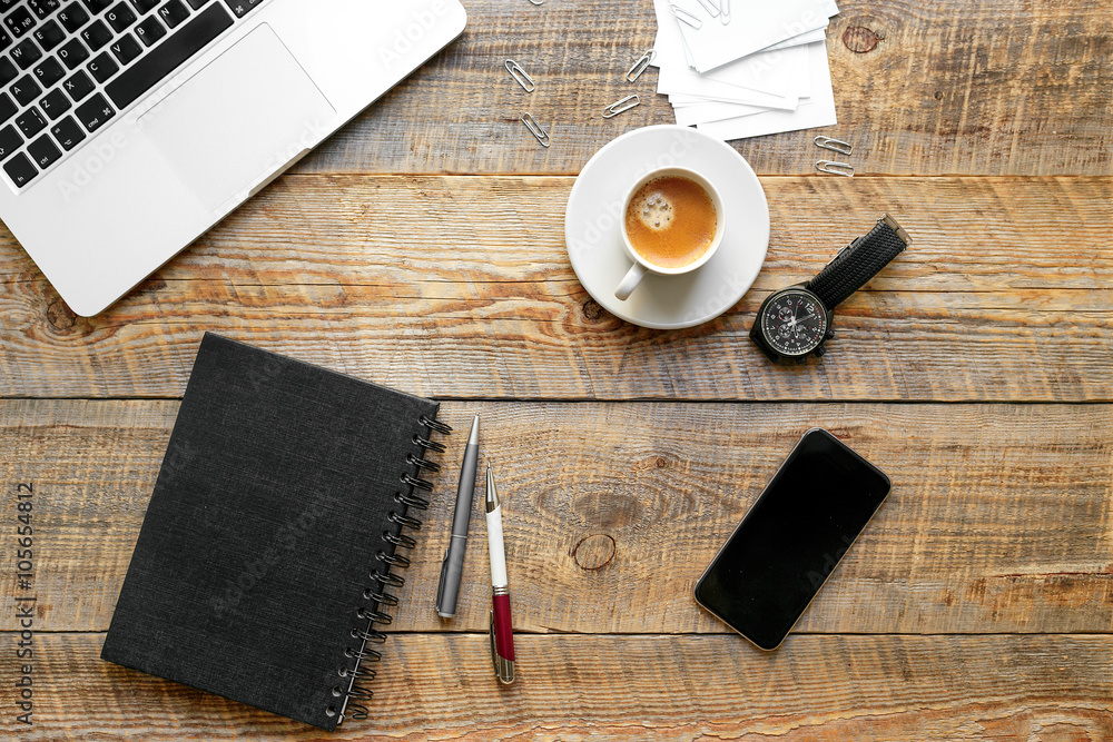 Working place with coffee cup, laptop, phone on wooden table