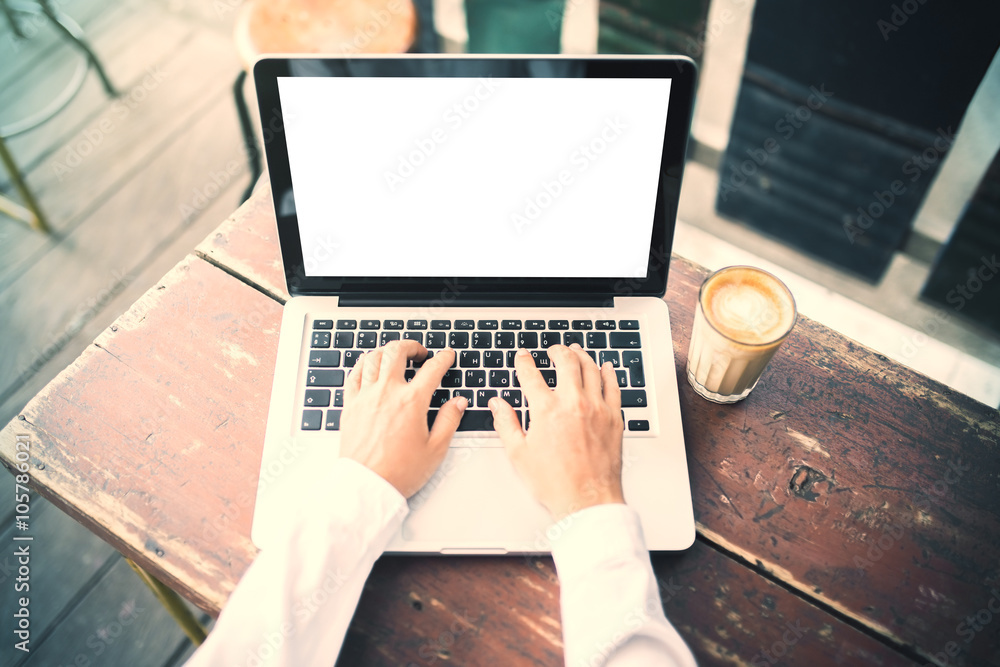 Girl typing on a laptop with cup of coffee outdoors, mock up