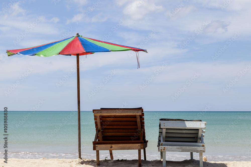 Two beach chairs and colorful umbrella on tropical beach,blue sk