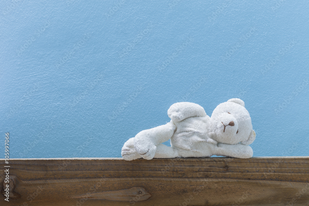  teddy bear sleep ,on old wood  and blue wall background.