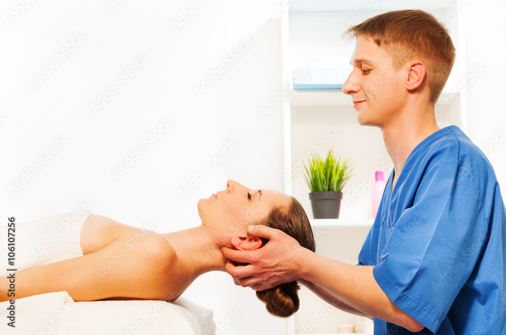 Masseur doing head massage on woman in spa salon