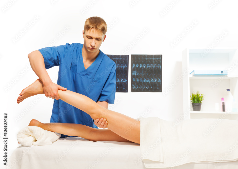 Masseur doing exercises with woman leg