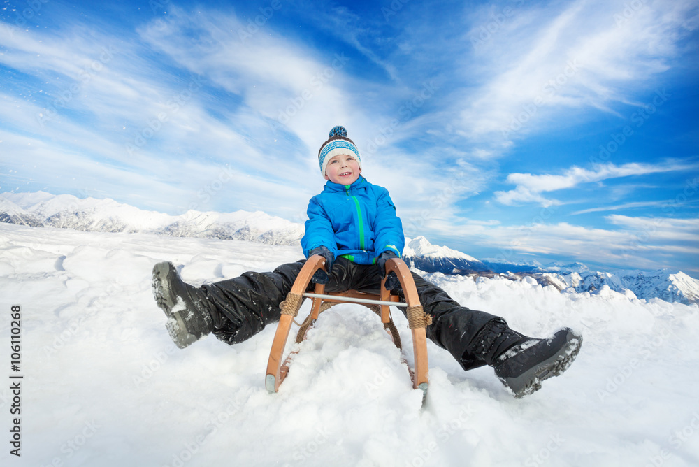 Winter fun in snow mountains boy on sledge