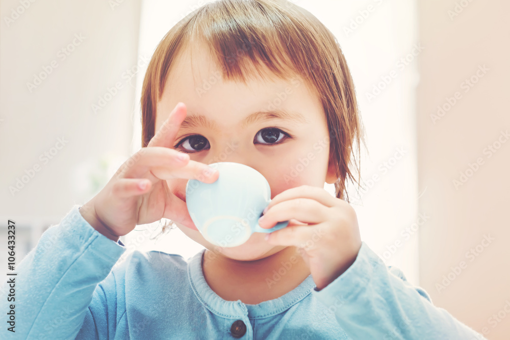 Happy toddler girl drinking from a teacup