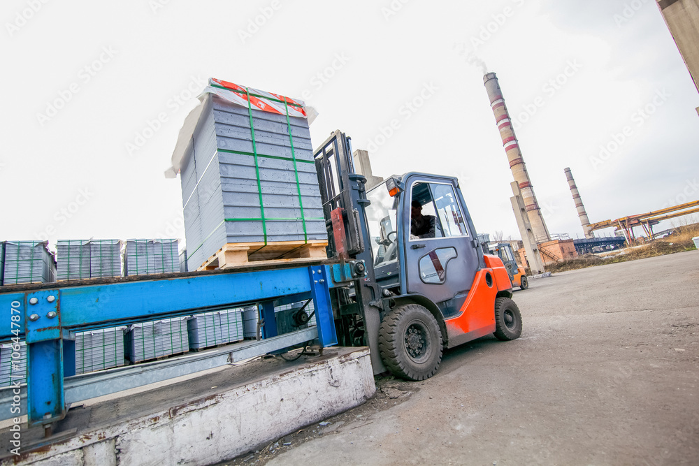 Auto loader with concrete blocks near house-building factory