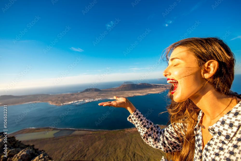 一个女人站在兰萨罗特岛的El Rio观景台上玩得很开心，Graciosa岛的美景尽收眼底