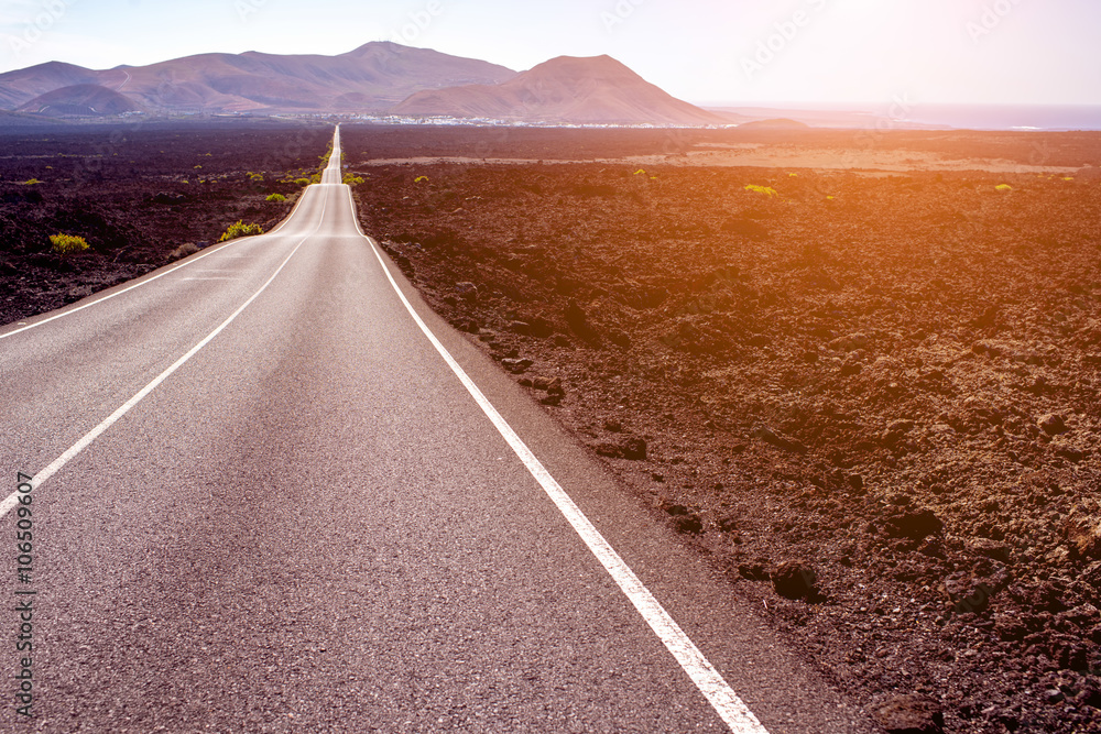 Highway on the deserted landscape on the sunset on Lanzarote island in Spain