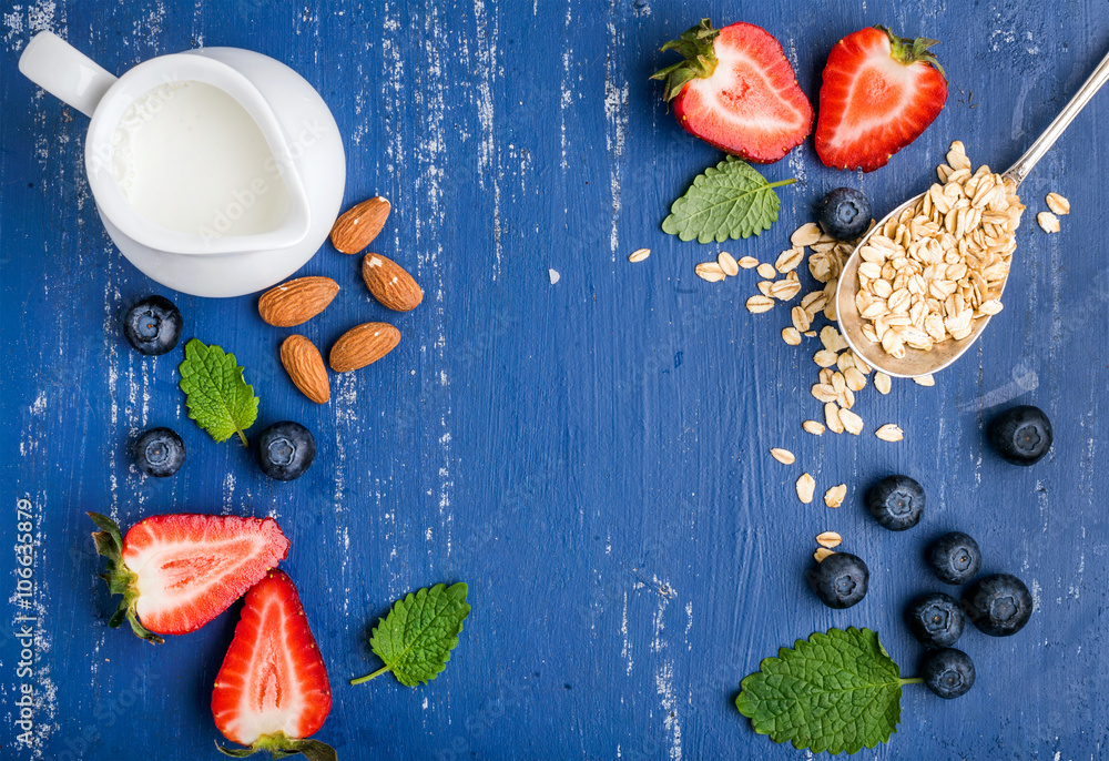 Healthy breakfast ingredients food frame. Oatmeal, milk in creamer, berries, almond and mint on pain