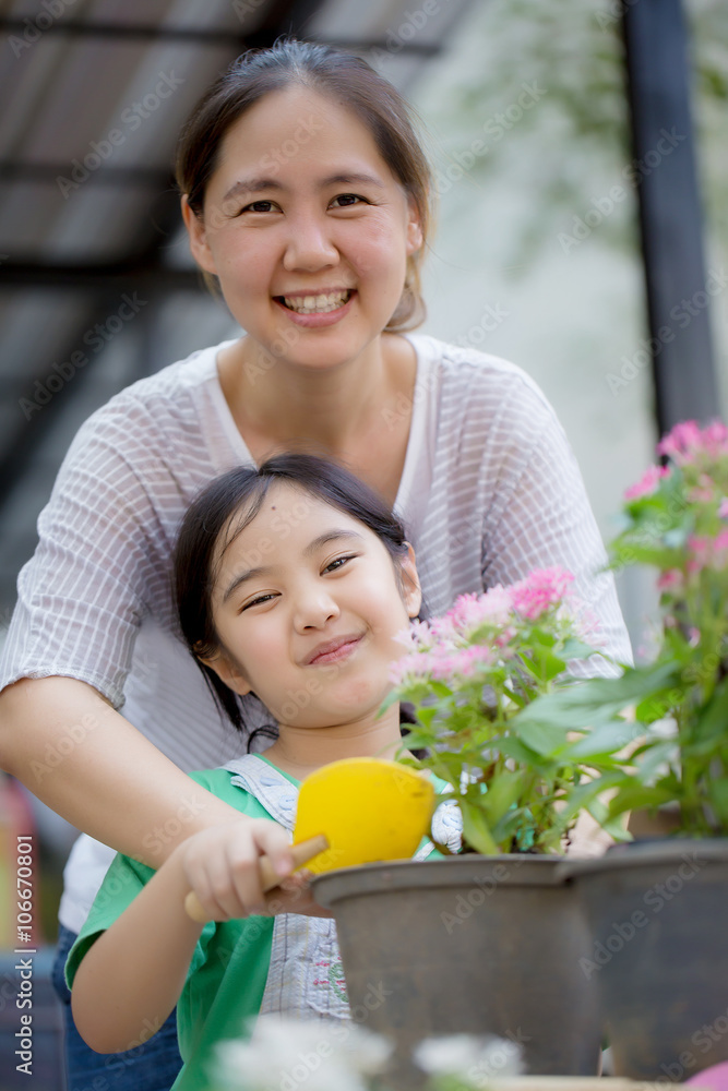 Little Asian child planting flower with her mother