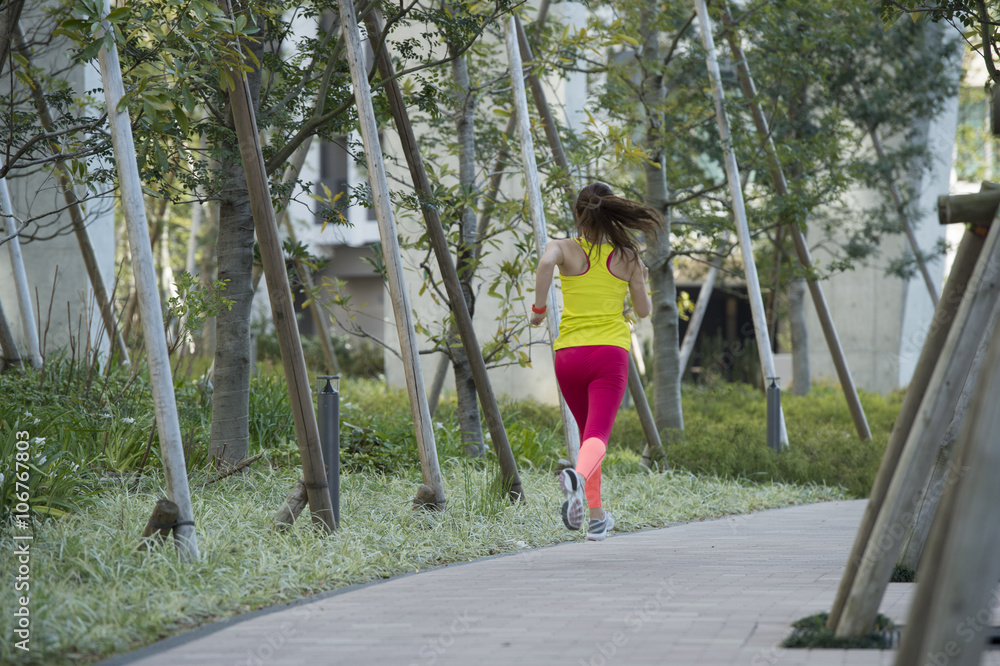 Back figure of a young woman jogging in the park