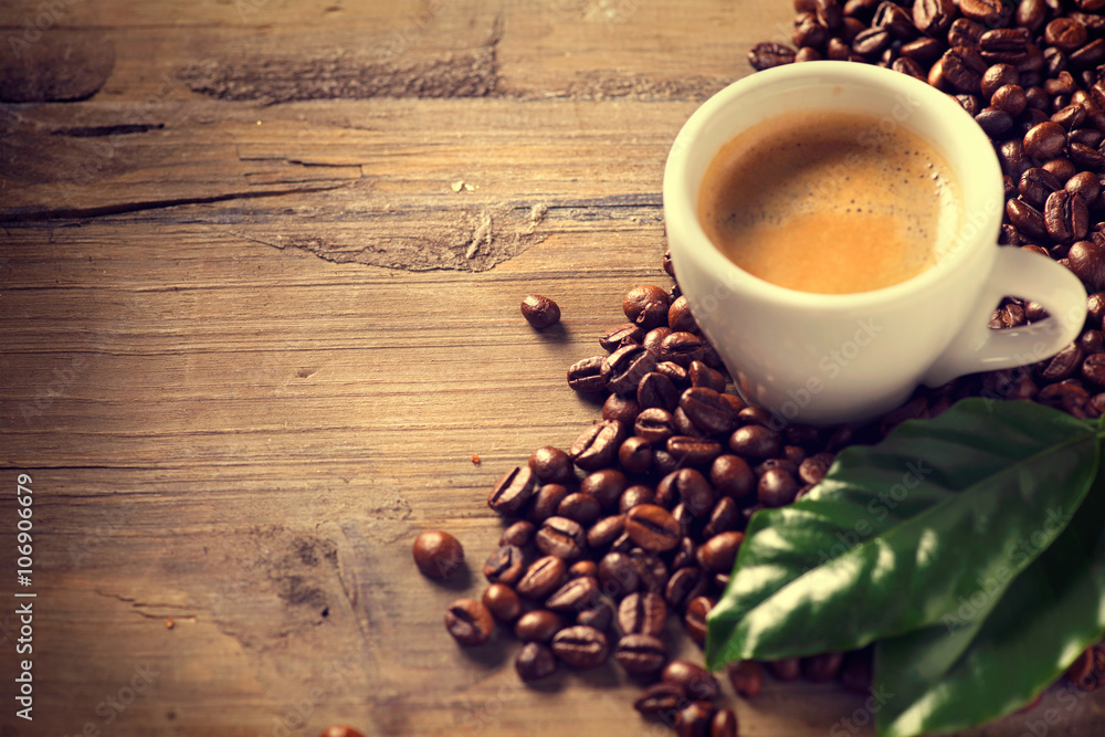 Cup of coffee on wooden background decorated with coffee beans