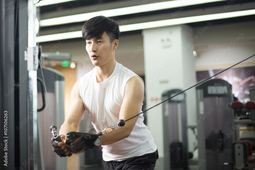 young handsome asian man works out in modern gym