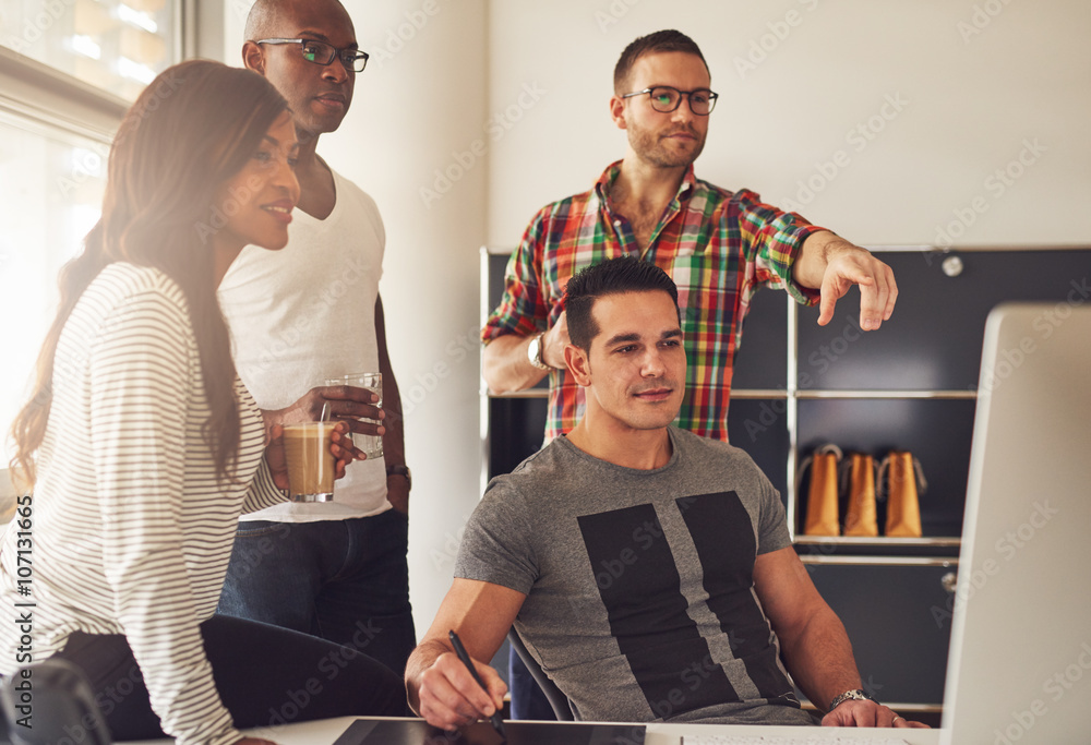 Man pointing at computer next to co-workers