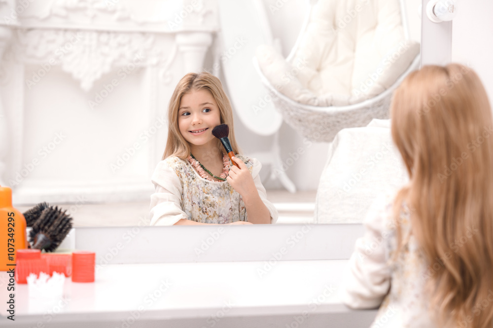 Cute little girl applying makeup