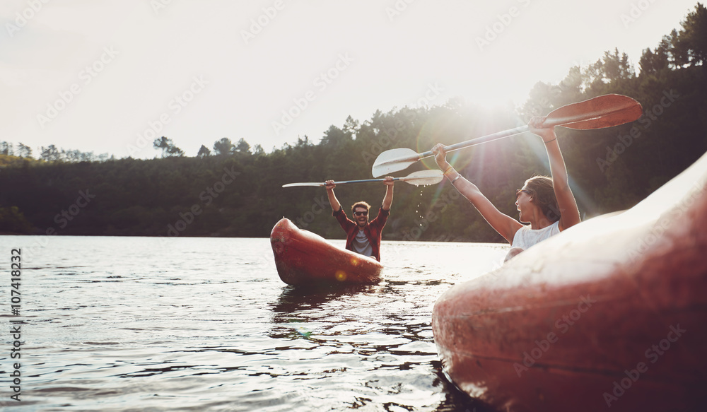 Happy young couple enjoying canoeing on summer day