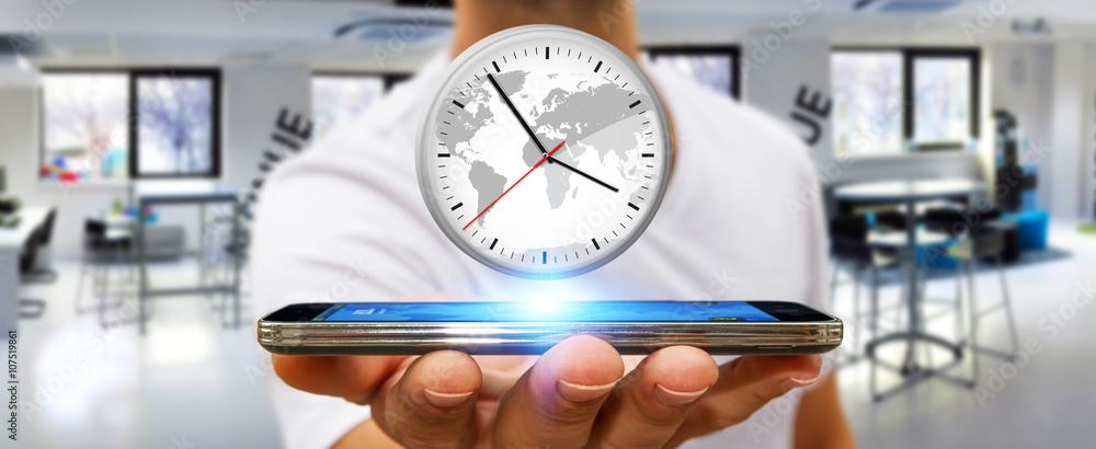 Businessman holding a clock over his mobile phone