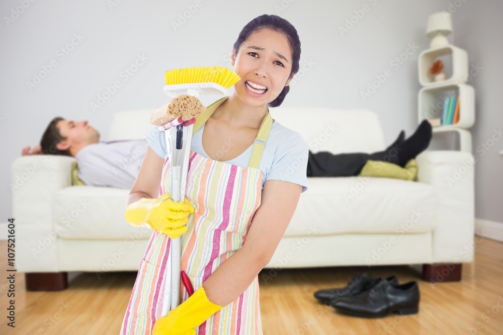 Composite image of distressed woman holding cleaning tools