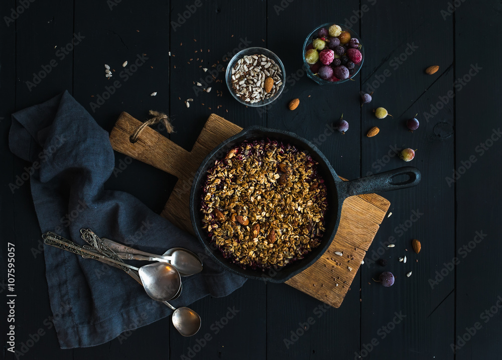 Healthy breakfast. Oat granola crumble with frozen fresh berries, and seeds in irom skillet pan on r