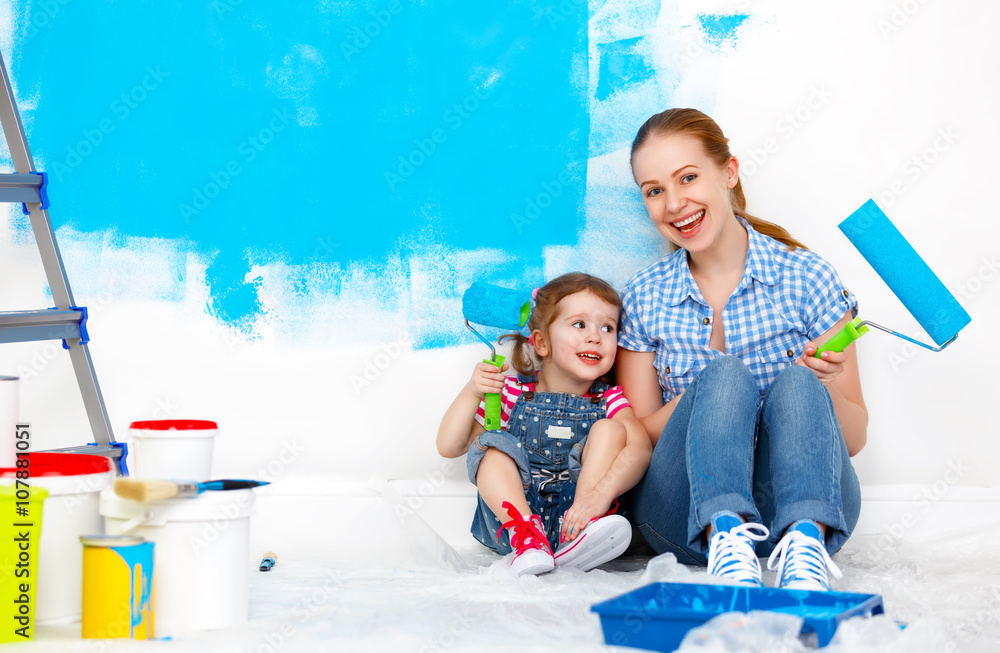 happy family mother and child daughter making repairs, paint wal