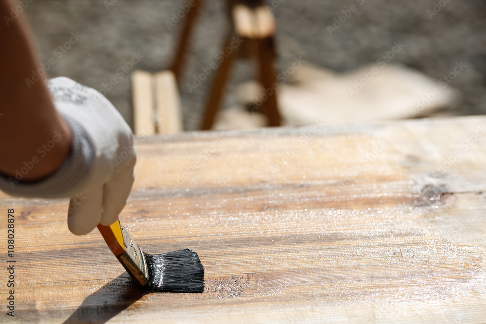 Painter painting wooden surface, protecting wood