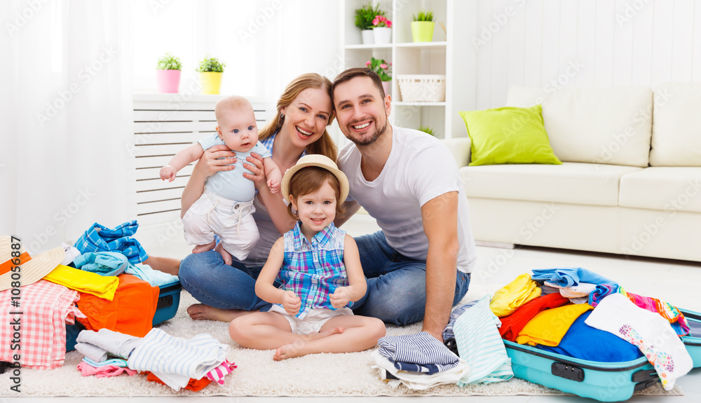 happy family mother, father and two children packed suitcases fo