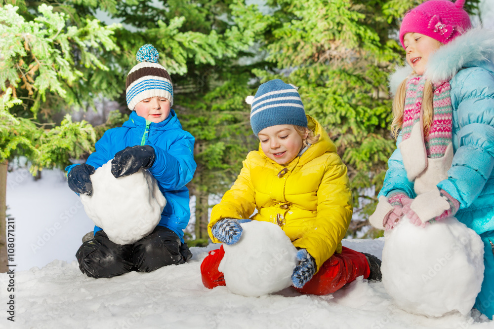 Kids roll snow balls in the park