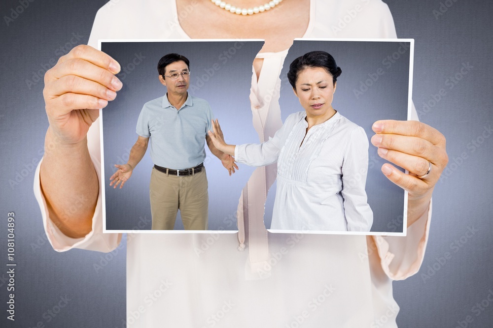 Composite image of woman holding a torn photo