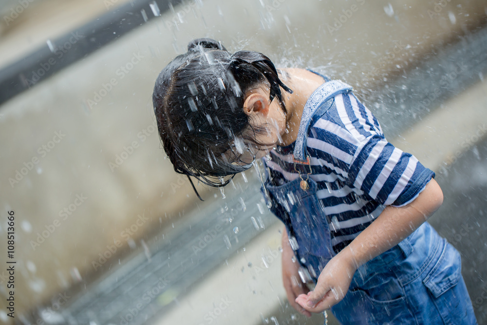 Asian girl playing with water fountain at water park