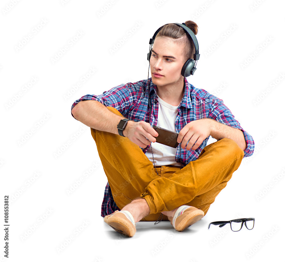 Young fashion man sitting on the floor and enjoying music