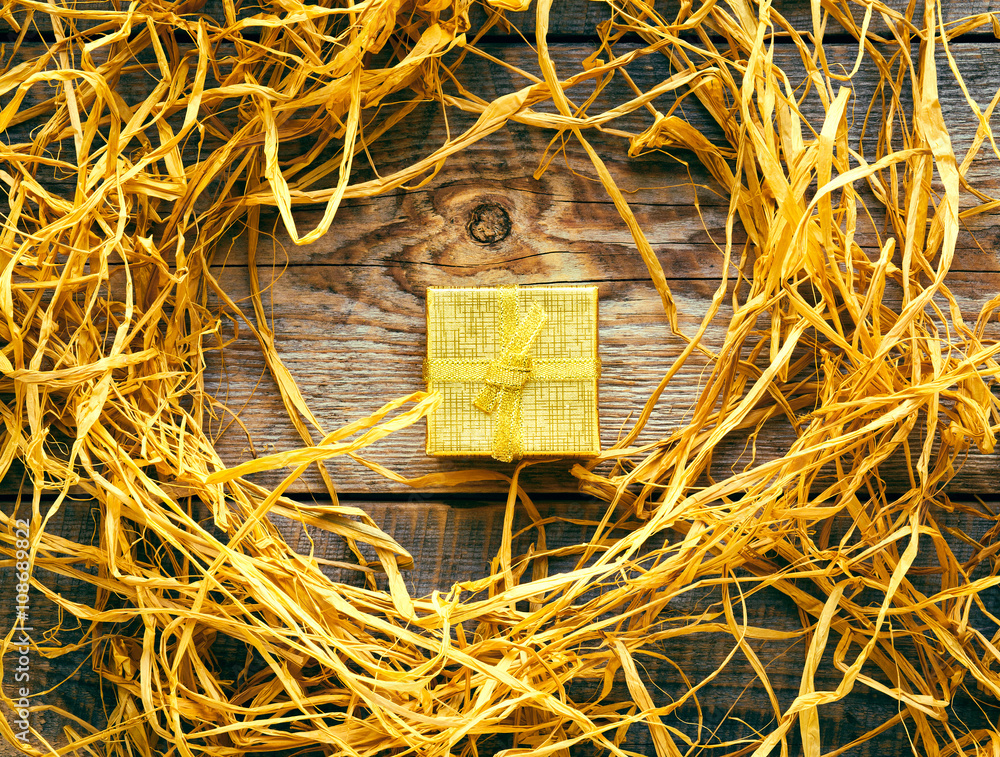 golden gift box on wooden table with raffia or twine