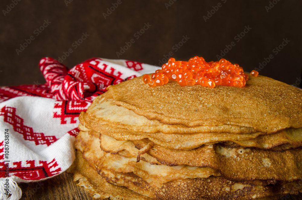 传统的俄罗斯煎饼配红色鱼子酱，木质乡村背景。Maslenitsa。