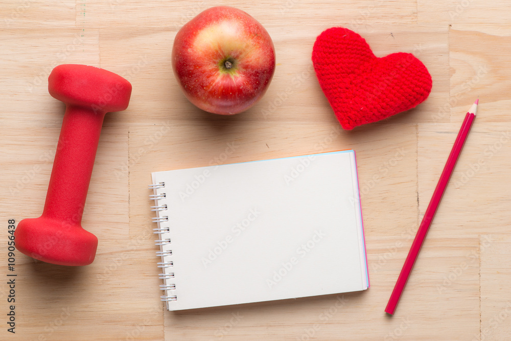 Fitness equipment. Healthy food. Apple, dumbbells and measuring tape on wooden background. View from