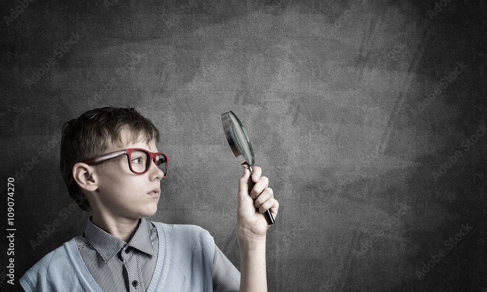 Curious school boy with magnifier