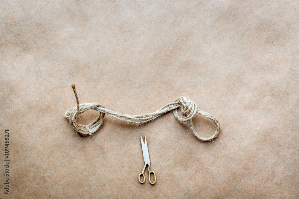 concept scissors cut knot on rope at background kraft paper