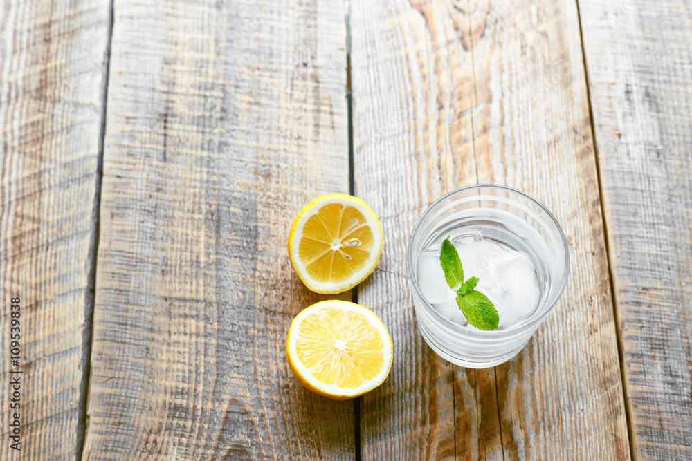 glass of lemonade with  lemons on wooden table close up