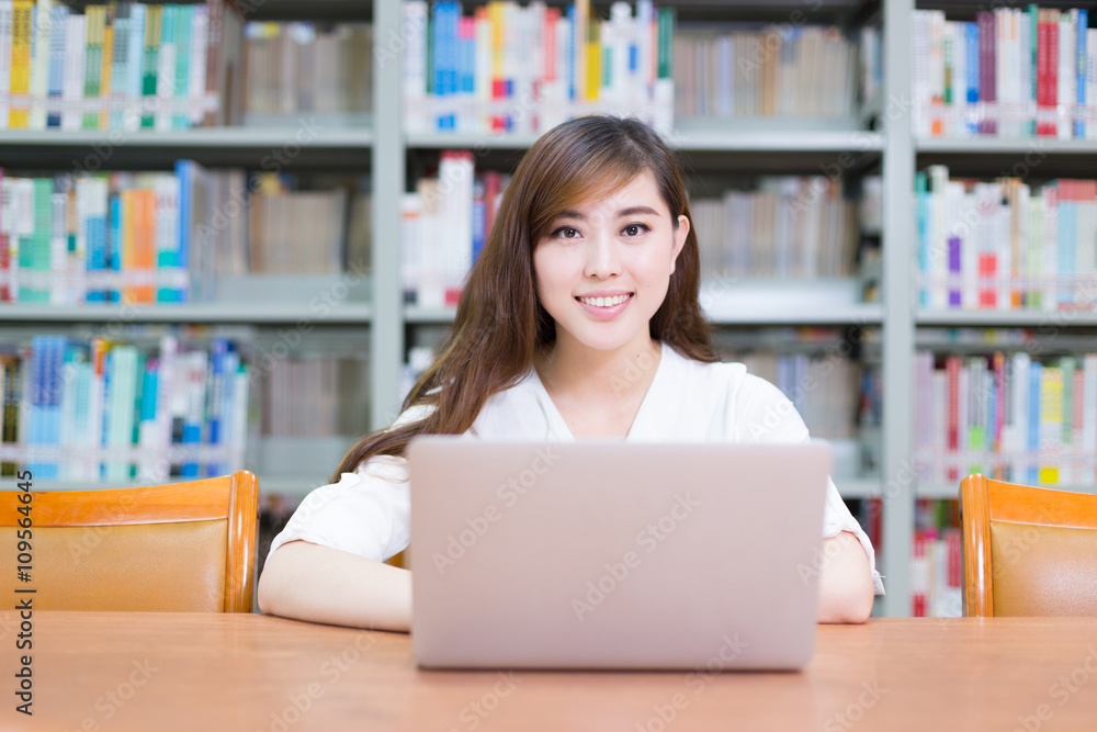 young beautiful asian girl with laptop in school library