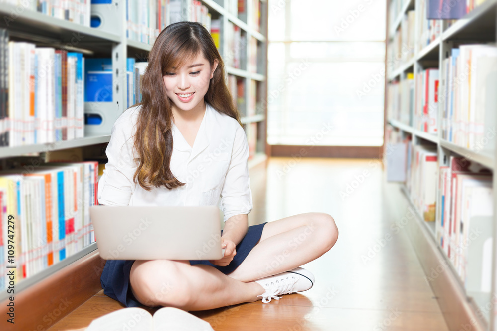 年轻漂亮的亚洲女大学生带着笔记本电脑在图书馆