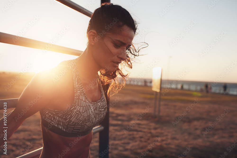 Sportswoman exercising on outdoor workout equipments