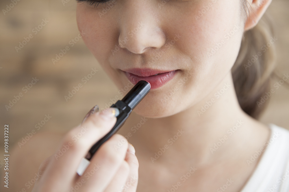 Young women are painted with lipstick while looking in the mirror